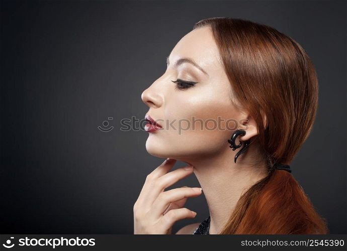 beautiful young redhead woman isolated on dark background with copyspace