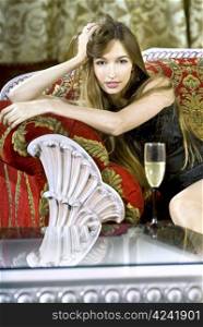 beautiful young rich woman near a coffee table with glass of fizz