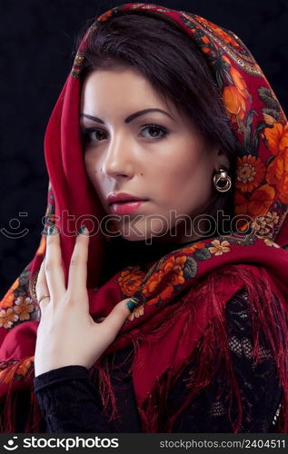 Beautiful young russian woman wearing red traditional russian shawl on black background