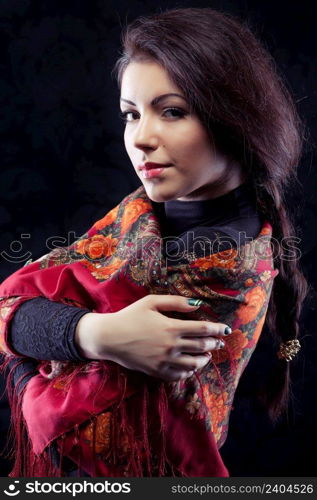 Beautiful young russian woman with braid in red traditional russian shawl on black background