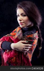 Beautiful young russian woman with braid in red traditional russian shawl on black background