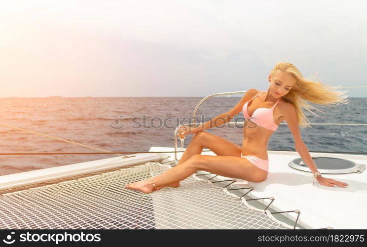 Beautiful young sexy blonde girl in a swim suit on a yacht or catamaran holding glass of wine at sunny summer day. Croatia. Europe. Beautiful young sexy blonde girl in a swim suit on a yacht holding glass of wine at sunny summer day. Croatia. Europe