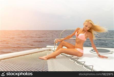 Beautiful young sexy blonde girl in a swim suit on a yacht or catamaran holding glass of wine at sunny summer day. Croatia. Europe. Beautiful young sexy blonde girl in a swim suit on a yacht holding glass of wine at sunny summer day. Croatia. Europe