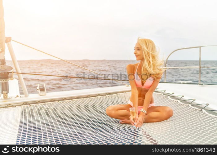 Beautiful young sexy blonde girl in a swim suit on a yacht or catamaran holding glass of wine at sunny summer day. Croatia. Europe. Beautiful young sexy blonde girl in a swim suit on a yacht holding glass of wine at sunny summer day. Croatia. Europe