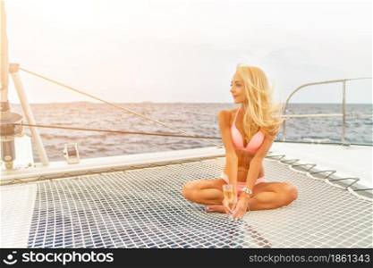 Beautiful young sexy blonde girl in a swim suit on a yacht or catamaran holding glass of wine at sunny summer day. Croatia. Europe. Beautiful young sexy blonde girl in a swim suit on a yacht holding glass of wine at sunny summer day. Croatia. Europe