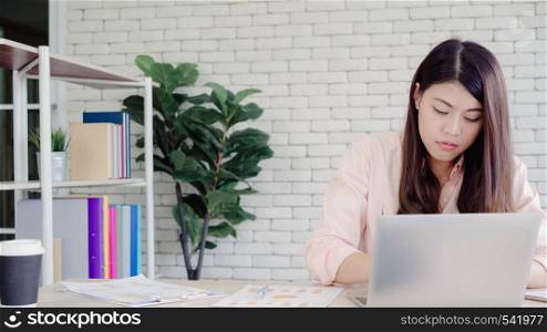 Beautiful young smiling asian woman working laptop on desk in living room at home. Asia business woman writing notebook document finance and calculator in home office. Enjoying time at home concept.