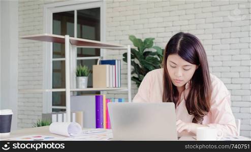 Beautiful young smiling asian woman working laptop on desk in living room at home. Asia business woman writing notebook document finance and calculator in home office. Enjoying time at home concept.