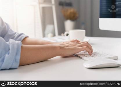 Beautiful young smiling asian woman working on laptop while sitt. Beautiful young smiling asian woman working on laptop while sitting in a living room at home. Asian business woman working in her home office. Enjoying time at home.