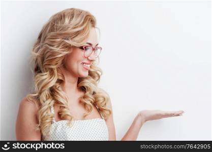 Beautiful young smiling woman in glasses presenting your very exciting product, white background with copy space. Woman in glasses presenting product