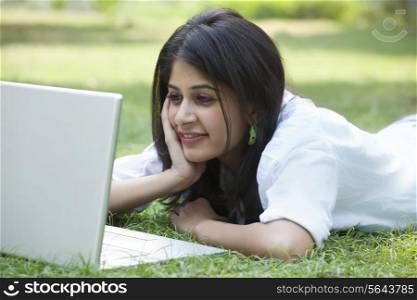 Beautiful young smiling woman using laptop on campus