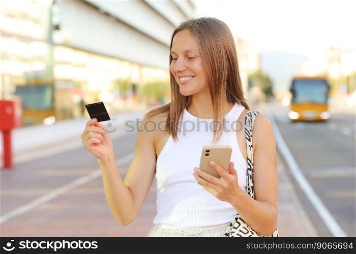 Beautiful young smiling woman with smartphone and credit card by the airport. Happy girl with suitcase after arrived airplane booking and paying for hotel. summer vacation. new abroad journey travel.. Beautiful young smiling woman with smartphone and credit card by the airport. Happy girl with suitcase after arrived airplane booking and paying for hotel. summer vacation. new abroad journey travel