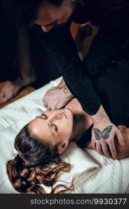 Beautiful young sporty woman enjoying shiatsu massage, lying  on the floor, wearing black clothes