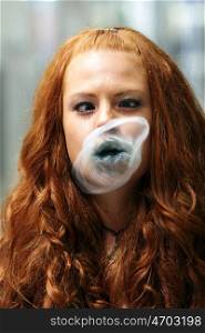 beautiful young student girl blowing bubble from chewing gum and looking into the camera