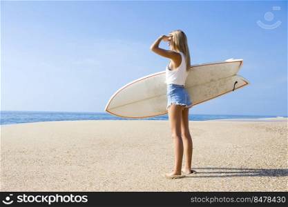 Beautiful young surfer girl checking the waves
