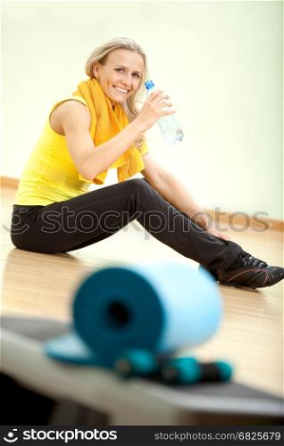 Beautiful young woman after fitness drinks water from a plastic bottle