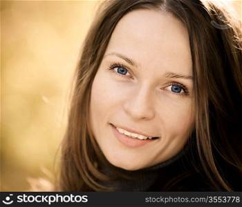 Beautiful young woman against blurred autumn background