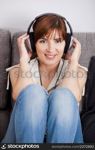 Beautiful young woman at home listening music with headphones