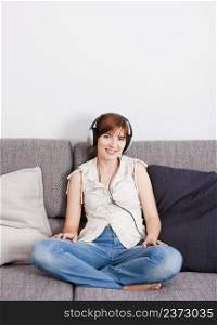 Beautiful young woman at home listening music with headphones