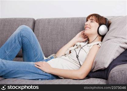 Beautiful young woman at home listening music with headphones