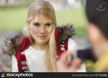 Beautiful young woman being photographed by man in park