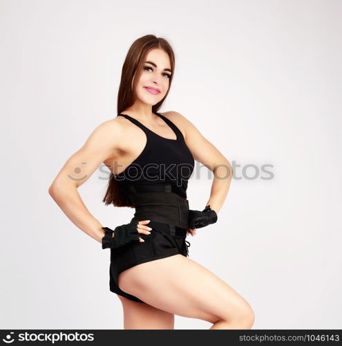 beautiful young woman bodybuilder with long blond hair standing and looking at the camera on a white background