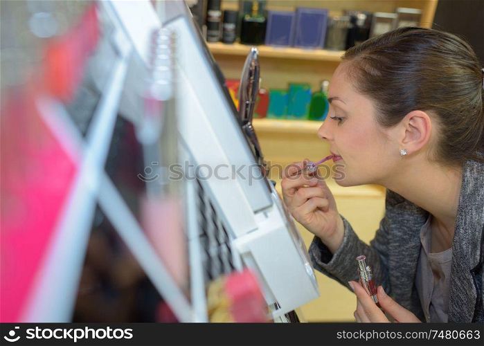 beautiful young woman buying lipstick