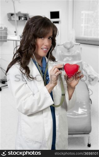 Beautiful young woman cardiologist doctor holding a heart