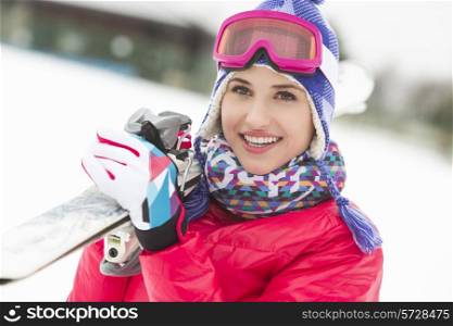Beautiful young woman carrying skis in snow