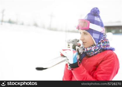 Beautiful young woman carrying skis outdoors