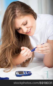 Beautiful Young Woman Checking Blood Sugar Level by Glucose Meter at Home. Medicine, Diabetes, Glycemia, Health Care Concept