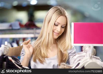 Beautiful young woman considers clothes in shop