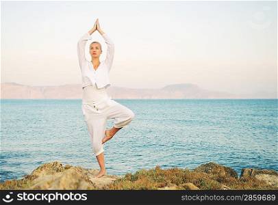 Beautiful young woman doing yoga exercise outdoors