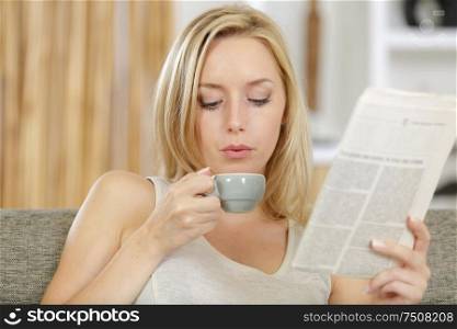 beautiful young woman drinking coffee and reading newspapers