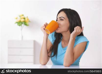 Beautiful young woman drinking coffee at home