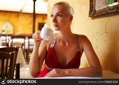 Beautiful young woman drinking coffee in a restaurant