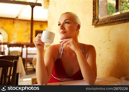 Beautiful young woman drinking coffee in a restaurant