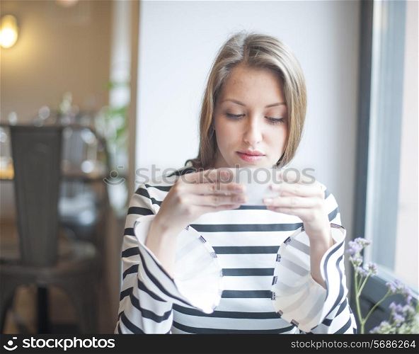 Beautiful young woman drinking coffee in cafe