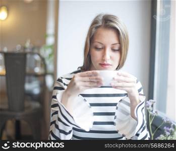 Beautiful young woman drinking coffee in cafe