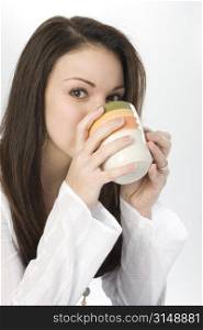 Beautiful young woman drinking from a coffee mug.
