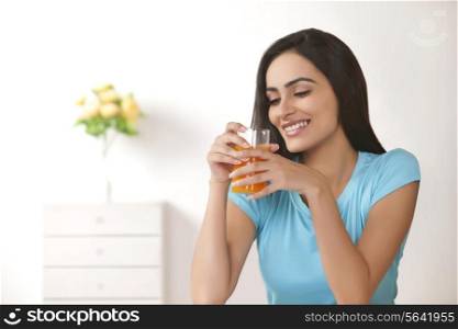 Beautiful young woman drinking glass of fresh orange juice at home
