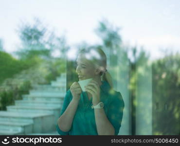 beautiful young woman drinking morning coffee by the window in her home