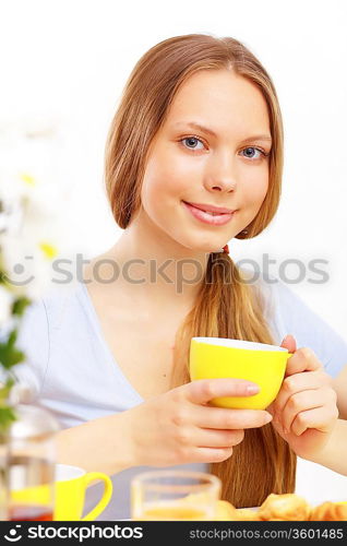 Beautiful young woman drinking tea from yellow cup