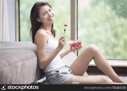 Beautiful young woman eating fruit
