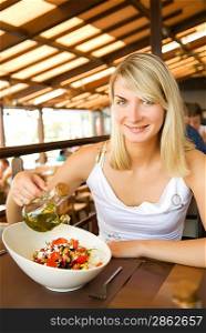 Beautiful young woman eating healthy vegetable salad in a restaurant