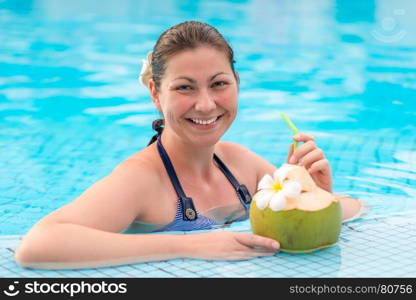 beautiful young woman enjoys delicious coconut milk while in the pool