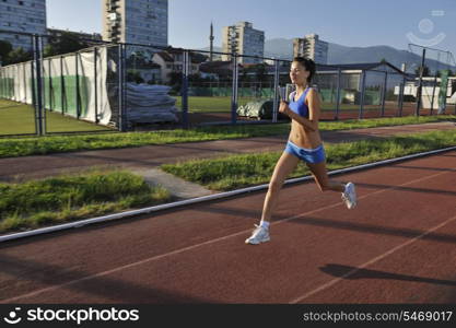 beautiful young woman exercise jogging and runing on athletic track on stadium at sunrise