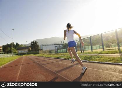 beautiful young woman exercise jogging and runing on athletic track on stadium at sunrise