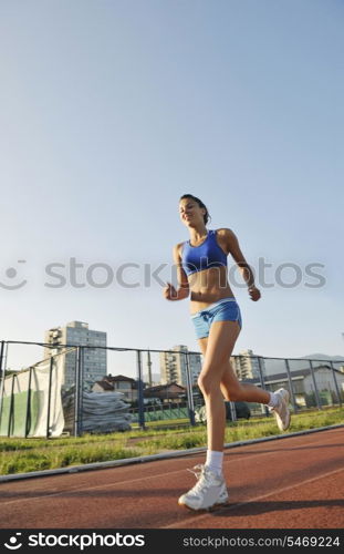 beautiful young woman exercise jogging and runing on athletic track on stadium at sunrise