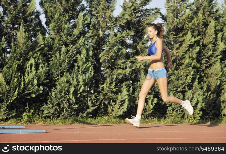 beautiful young woman exercise jogging and runing on athletic track on stadium at sunrise