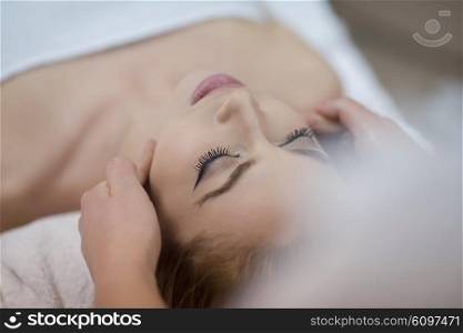 beautiful young woman getting face and head massage in spa and wellness salon